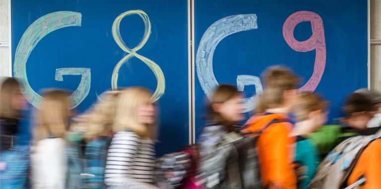Schülerinnen und Schüler vor einer Tafel, die mit G8 und G9 beschrieben wurde.