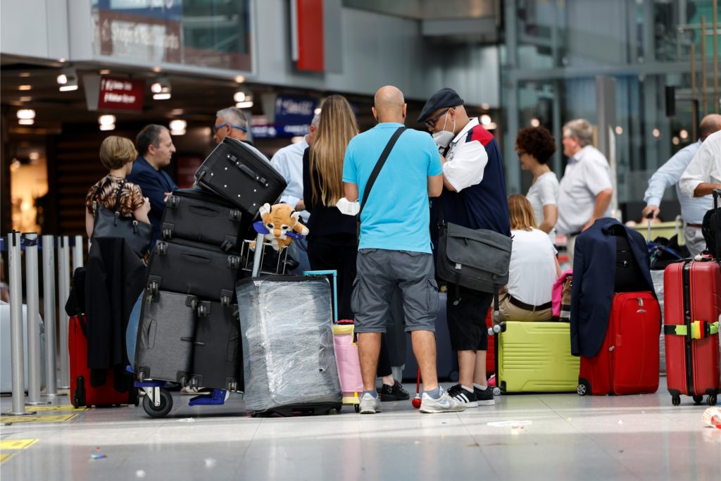 Passagiere stehen an Check-In Schalter der jeweiligen Airlines am Flughafen Düsseldorf an.