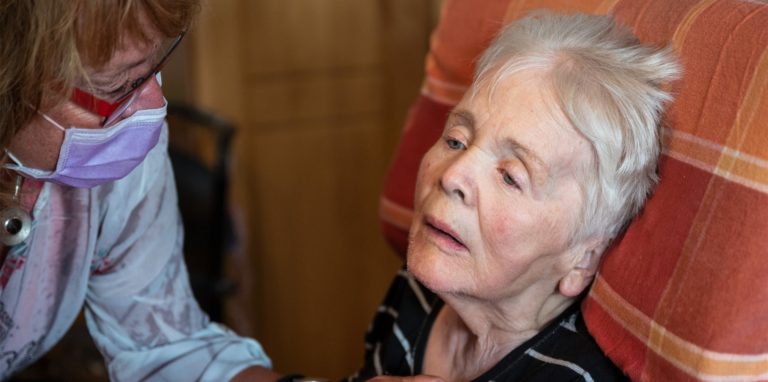 Birgit Rückert, Leiterin eines ambulanten Dienstes, drückt einer an Demenz und Parkinson erkrankten Patientin die Hand.