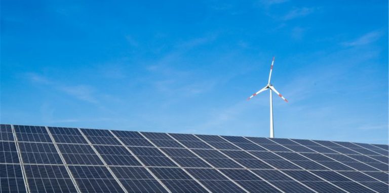 Ein Windrad hinter einem Solarfeld.