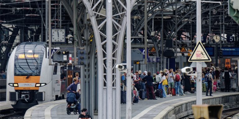 Reisende warten auf einem Bahnsteig im Hauptbahnhof auf ihren Zug.