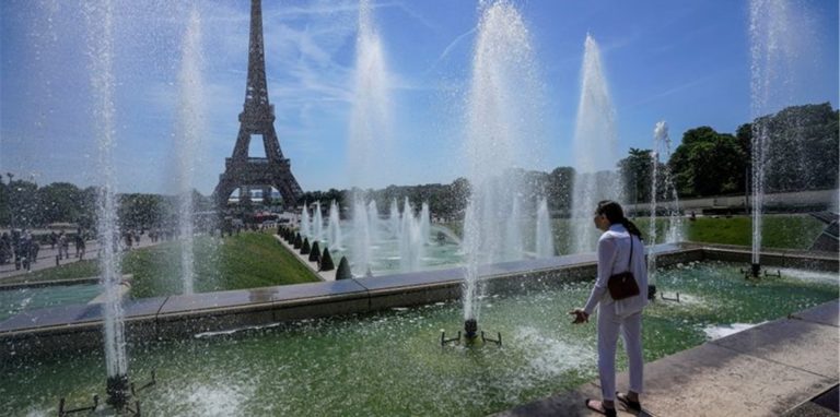 Eine Frau kühlt sich an einem Brunnen in der Nähe des Eiffelturms ab.