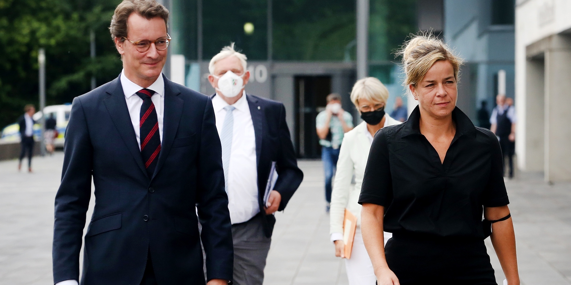 Der nordrhein-westfälische Ministerpräsident Hendrik Wüst (CDU), Wirtschaftsministerin Mona Neubaur (Grüne) (vorne r), Gesundheitsminister Karl-Josef Laumann (CDU) und Schulministerin Dorothee Feller (hinten r) gehen im Landeszentrum Gesundheit Nordrhein-Westfalen gemeinsam zur Pressekonferenz.