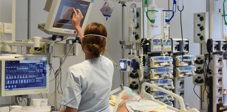 Auf der Intensivtherapie-Station (ITS) steht eine Mitarbeiterin am Bett einer Patientin.