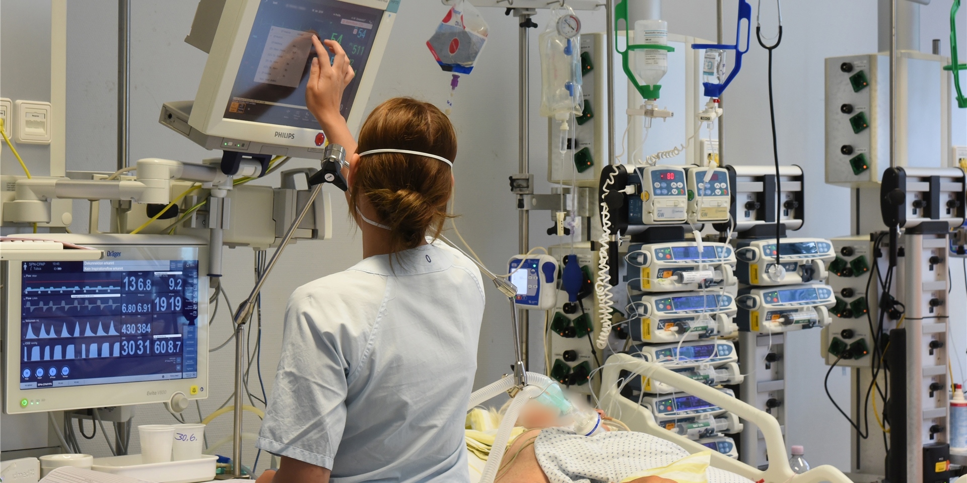 Auf der Intensivtherapie-Station (ITS) steht eine Mitarbeiterin am Bett einer Patientin.