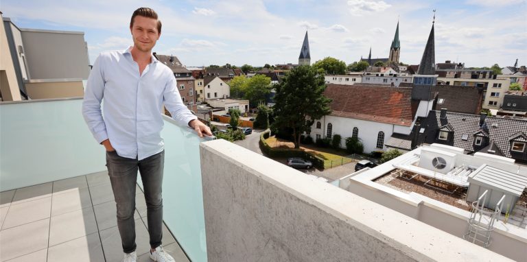 Projektleiter Maximilian Kirchhoff auf dem Ost-Balkon des Penthauses der Villa Möcking. Von dort gibt es einen spektakulären Blick auf die Innenstadt. Auf dem Stadthaus der Villa sind die Luft-Wasser-Wärmepumpen (unten rechts) installiert, die die Villa mit Energie versorgen.