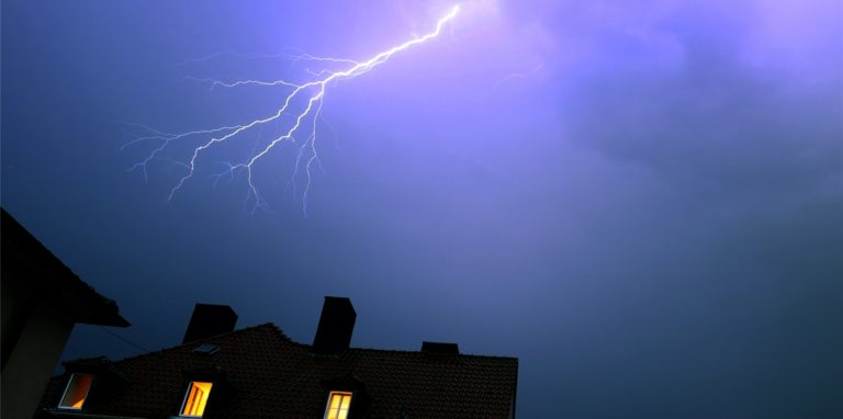 Blitze entladen sich während eines Gewitters über einem Wohnhaus.