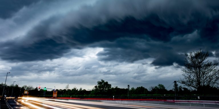 Dunkle Gewitter-Wolken ziehen sich über einer Straße zusammen