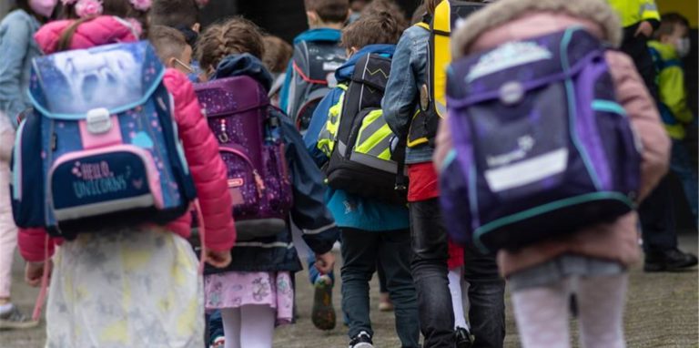 Kinder mit Schulranzen gehen in einer Gruppe.