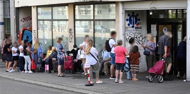 Menschen stehen in einer Schlange und warten vor einem Tafelladen.