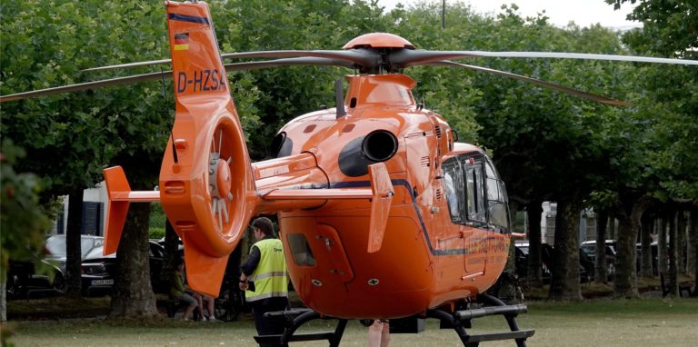 Ein Rettungshubschrauber und ein Polizeiauto stehen auf den Rheinwiesen in Düsseldorf.