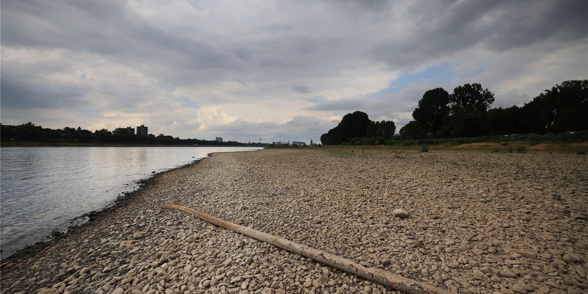 Wolken ziehen am Rhein über den bei niedrigem Pegelstand freigelegten Uferbereich.