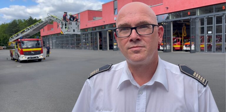 Dortmunds Feuerwehr-Chef Dirk Aschenbrenner steht vor einem Einsatzwagen mit Drehleiter.