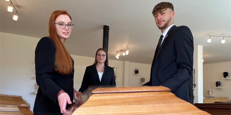 Jennifer Krane, Mathilda Lehmann und Fridolin Menne halten einen Sargdeckeln in der Hand.