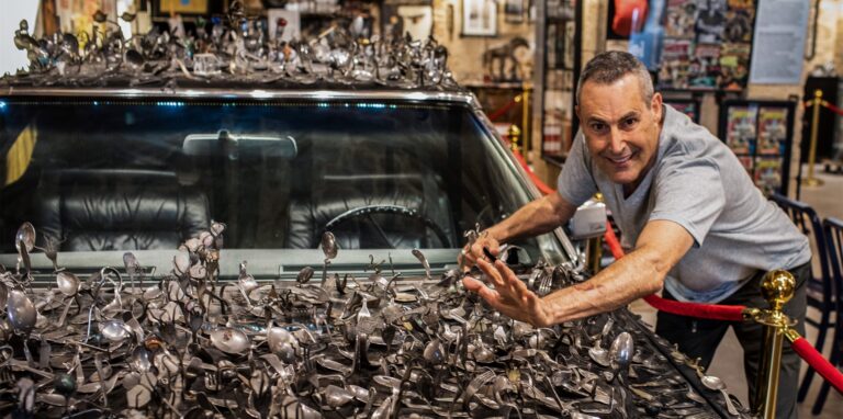 Der israelisch-britische Illusionist und TV-Persönlichkeit Uri Geller posiert neben einem Cadillac aus dem Jahr 1976, der mit selbst gebogenem Besteck bedeckt ist, in seinem Museum.