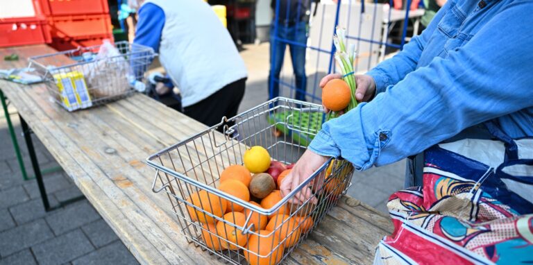 Eine bedürftige Frau steckt den Einkauf in einem Tafel-Laden in ihre Tasche.