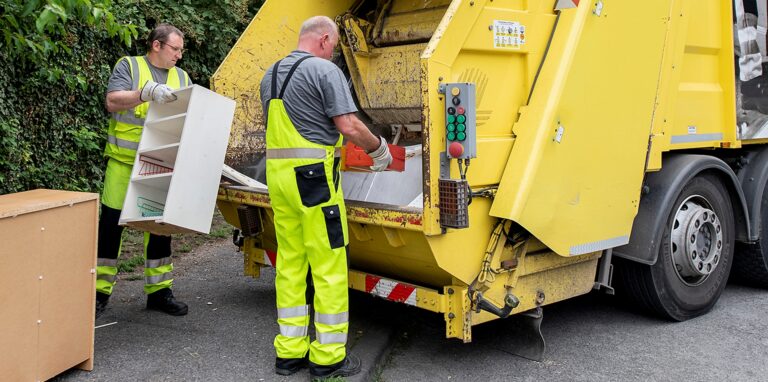 Zwei Müllwerker der EDG entsorgen Sperrmüll in einem Müllwagen.