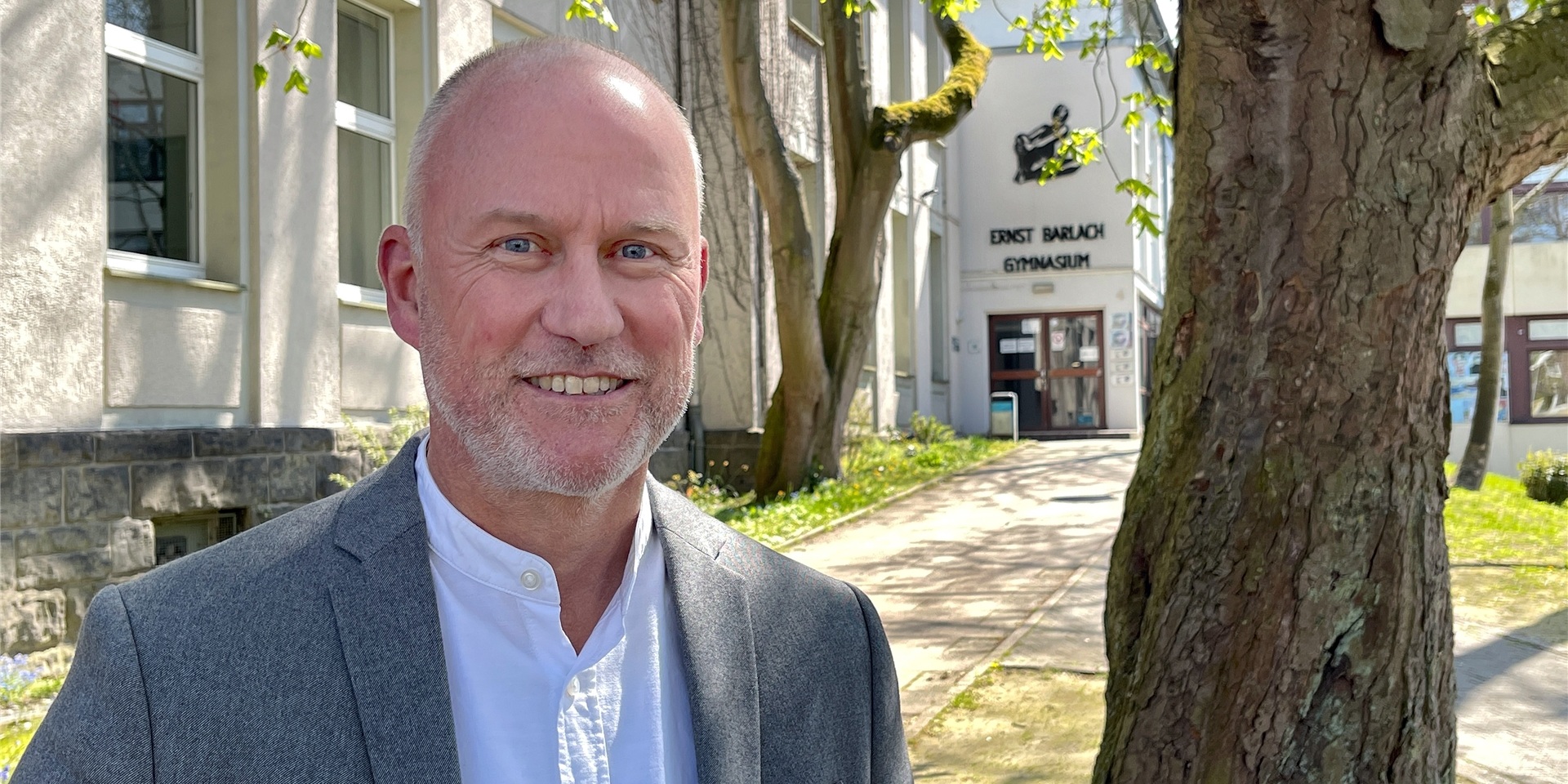 Schulleiter Ulrich Schmitz steht lächelnd vor dem Ernst-Barlach-Gymnasium.