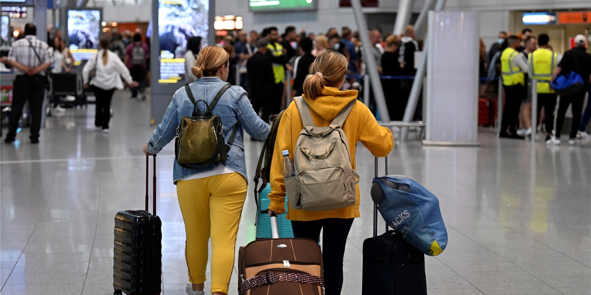 Passagiere gehen mit Gepäck durch durch ein Terminal am Flughafen.