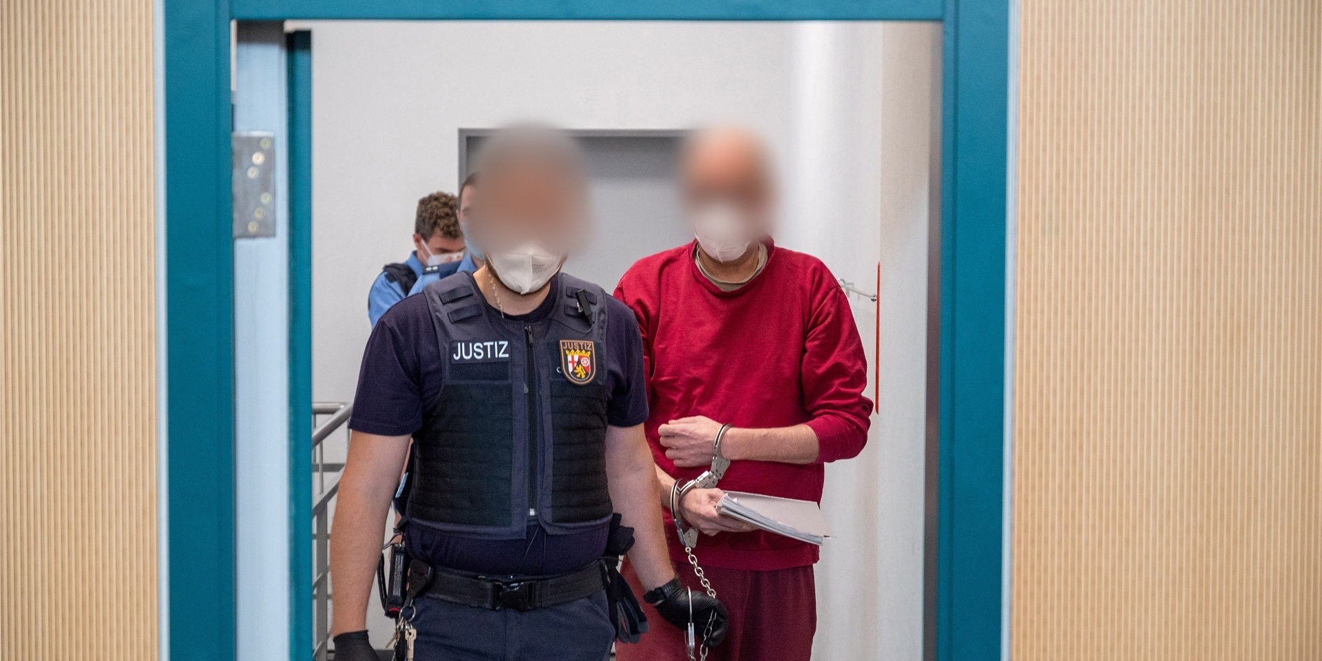 Ein Justizbediensteter begleitet den 52-jährigen Angeklagten (r) zum Prozess um die tödliche Amokfahrt in Trier in den Gerichtssaal des Landgerichts.