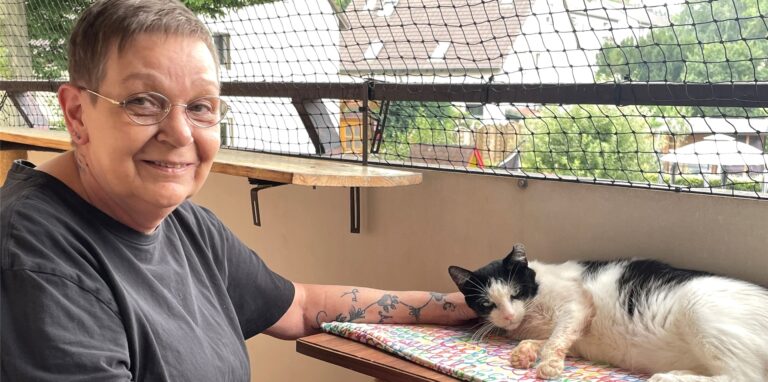 Andrea Henrich sitzt neben Kater Zecke und streichelt ihn.