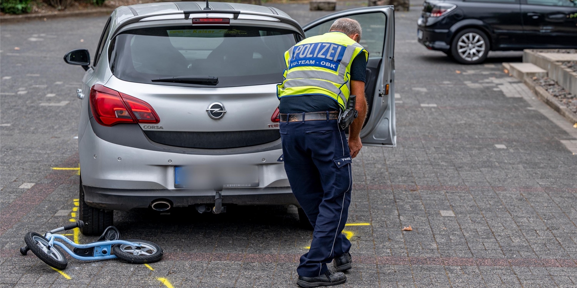 Die Polizei markiert die Unfallstelle auf einem Parkplatz, wo ein Zweijähriger von einem Auto angefahren und schwer verletzt worden war.