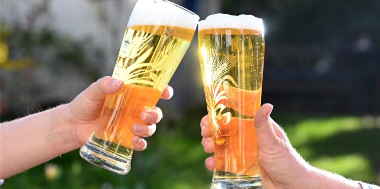 Mit Bier gefüllte Gläser stoßen an.
