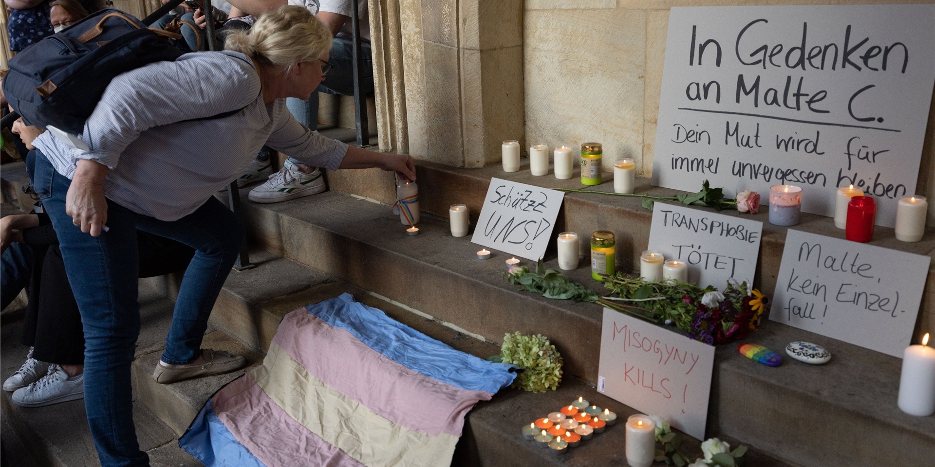 Eine Frau entzündet eine Kerze in Gedenken an Malte C.. Menschen demonstrieren auf dem Prinzipalmarkt gegen Gewalt an queeren Menschen.
