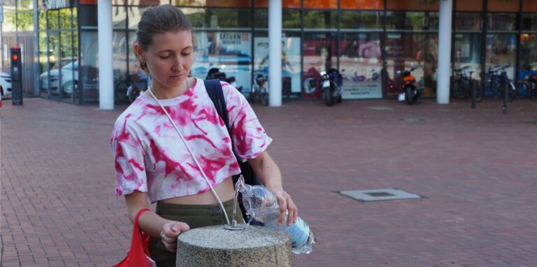 Orlanda (30) füllt sich vor dem Rathaus Trinkwasser ab. „Von diesen Trinkwasserspendern sollte es mehr geben“, sagt sie.
