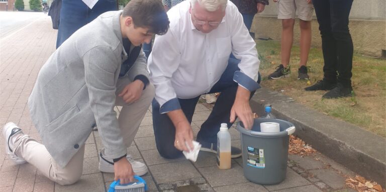Matteo Weitner und Hartmut Ganzke reinigen einen Stolperstein.
