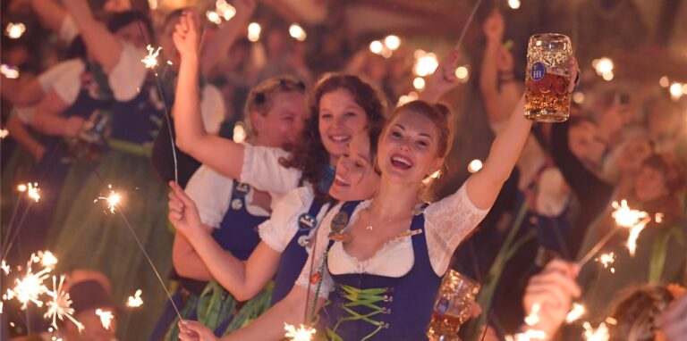 Bedienungen stehen im Hofbräu-Zelt beim traditionellen Kehraus auf den Tischen, halten dabei Wunderkerzen in den Händen und feiern damit das Ende der harten Arbeit auf der Wiesn.