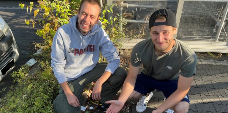 Justus Scherding und Jan Brückhändler zeigen den Müll auf dem Netto-Parkplatz in Holzwickede