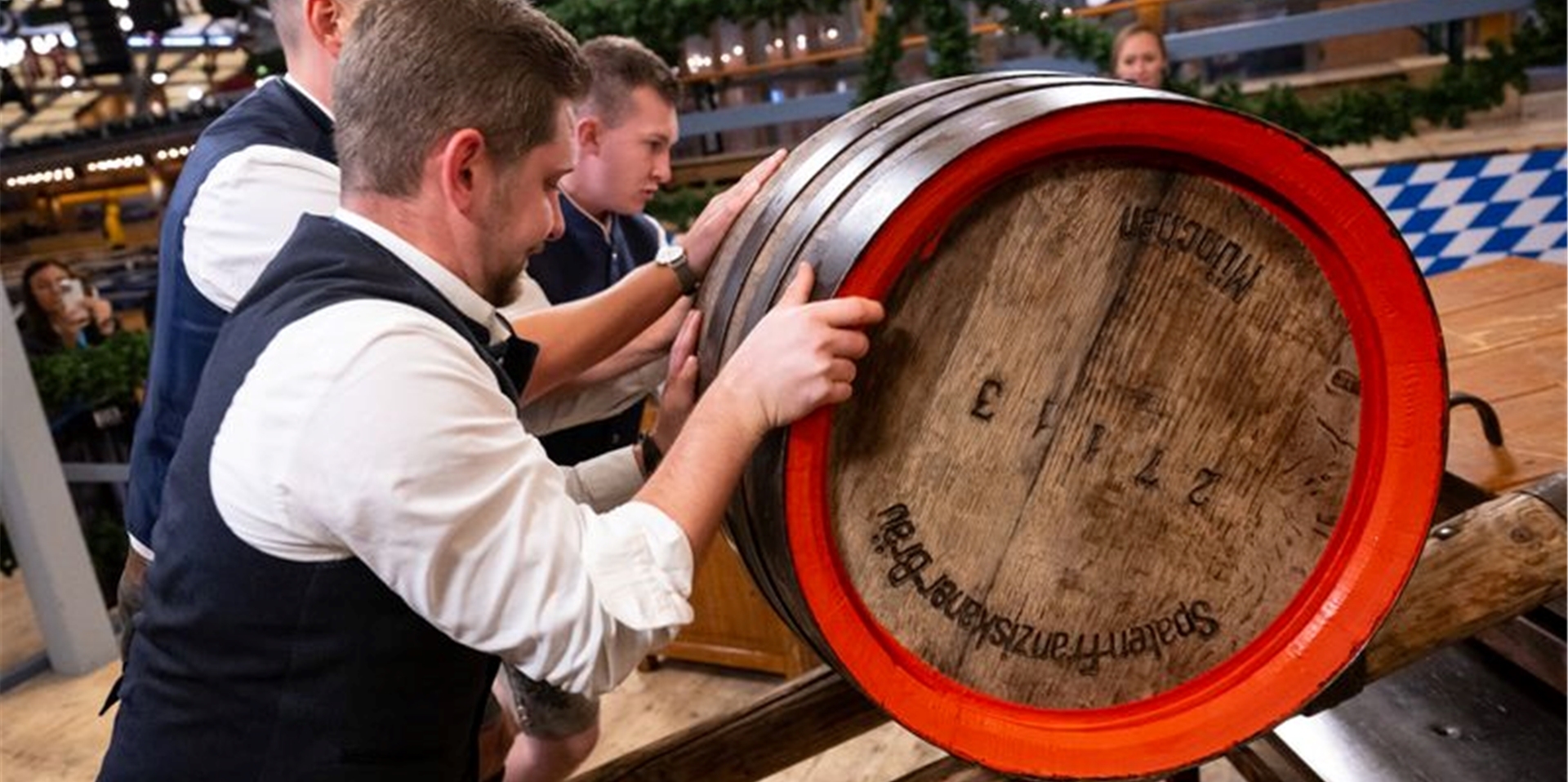Mitarbeiter rollen das Bierfass für den traditionellen Fassanstich in ein Festzelt.