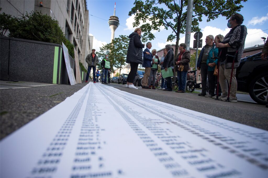 Betroffene des Bottroper Apothekerskandals haben ein meterlanges Plakat mit mehr als 2.000 Namen der Opfer vor dem Ministerium für Arbeit, Gesundheit und Soziales des Landes Nordrhein-Westfalen in Düsseldorf ausgerollt.
