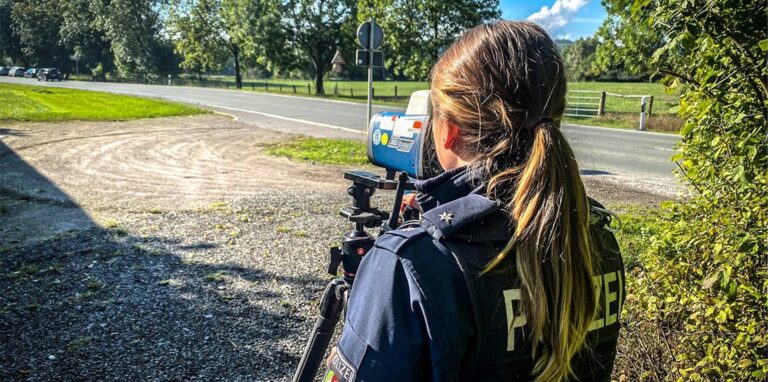 Eine Polizeibeamtin misst mit einem Lasergerät das Tempo an einer Straße im Kreis Unna