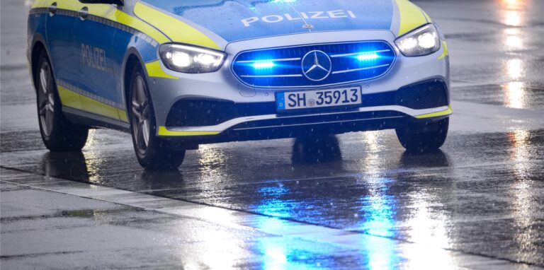 Ein Streifenwagen steht mit Blaulicht auf der regennassen Autobahn.