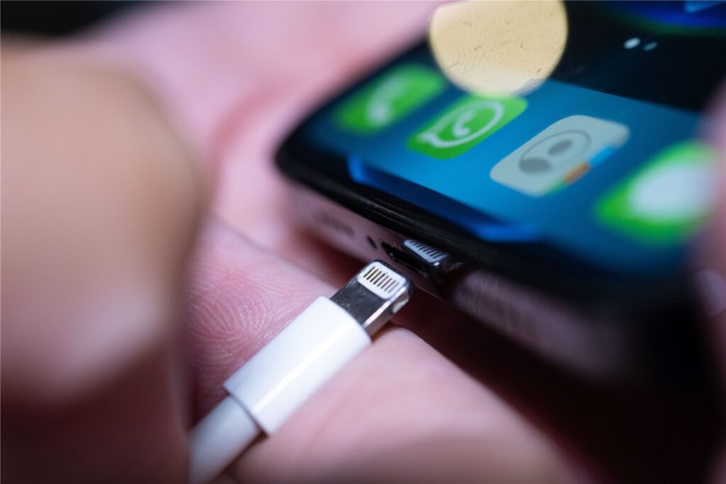 Ein Lightning-Ladestecker wird in ein Apple iPhone gesteckt. 