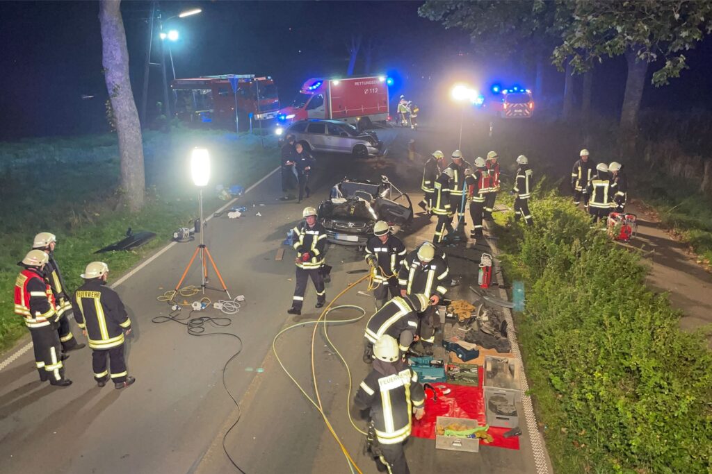 Feuerwehrleute stehen um das Autowrack herum.