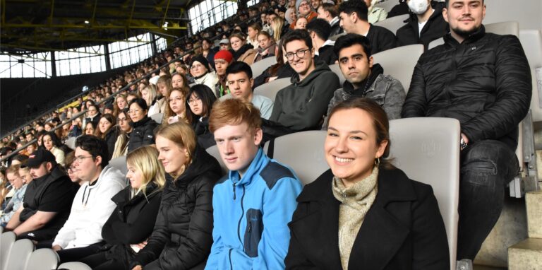 Tausende Neu-Studierende sitzen auf der Nordtribüne im Stadion.