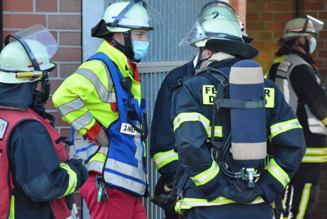 Feuerwehrleute unterhalten sich am Rande eines Einsatzes.