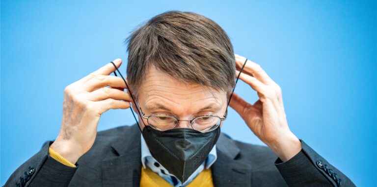 Karl Lauterbach zieht sich eine Maske auf.