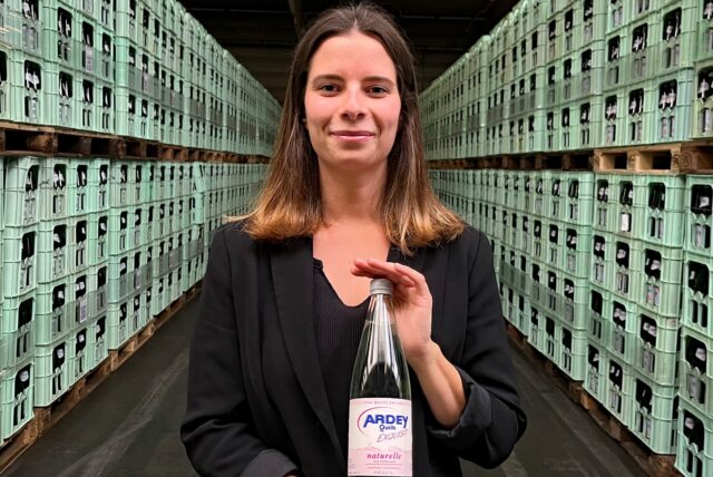 Sommelière Annika Kosubek präsentiert eine Flasche Ardey-Mineralwasser in der großen Lagerhalle der Dortmunder Ardey-Quelle