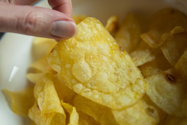 Eine Frau greift nach Kartoffelchips.