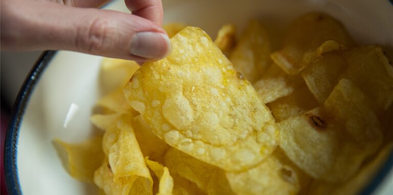 Eine Frau greift nach Kartoffelchips.