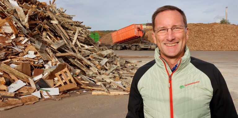 Olav Meyer steht neben einem Berg von Altholz.