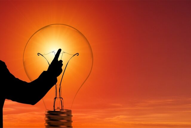 Ein Mann und eine Glühbirne vor einer Sonne: ein Symbolbild für Strom.