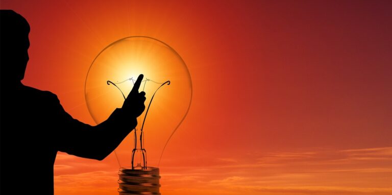 Ein Mann und eine Glühbirne vor einer Sonne: ein Symbolbild für Strom.
