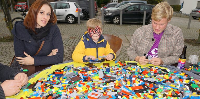 Eine Familie sitzt an einem Tisch voller Lego.