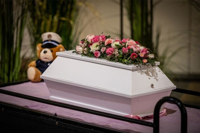 Der winzige weiße Sarg des getöteten Säuglings Rabea mit zwei Blumengestecken ist in der Trauerhalle während der Trauerfeier auf dem Hauptfriedhof Mönchengladbach aufgestellt.