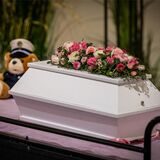 Der winzige weiße Sarg des getöteten Säuglings Rabea mit zwei Blumengestecken ist in der Trauerhalle während der Trauerfeier auf dem Hauptfriedhof Mönchengladbach aufgestellt.